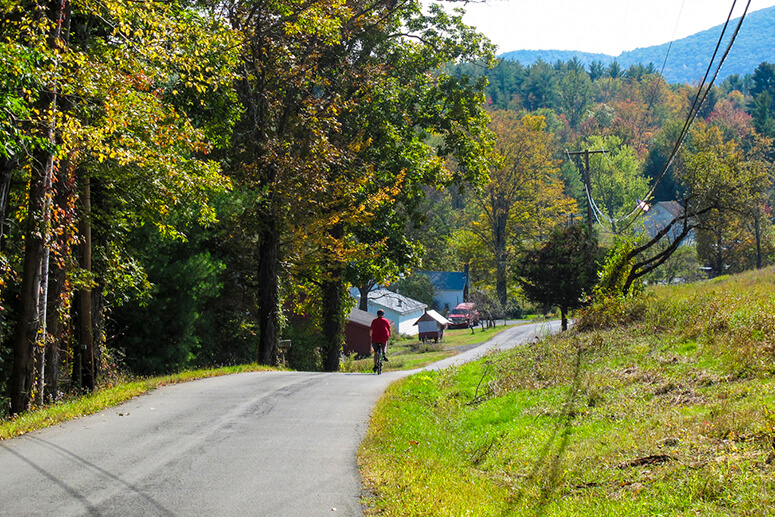 A cyclist rides a mountain road in fall.