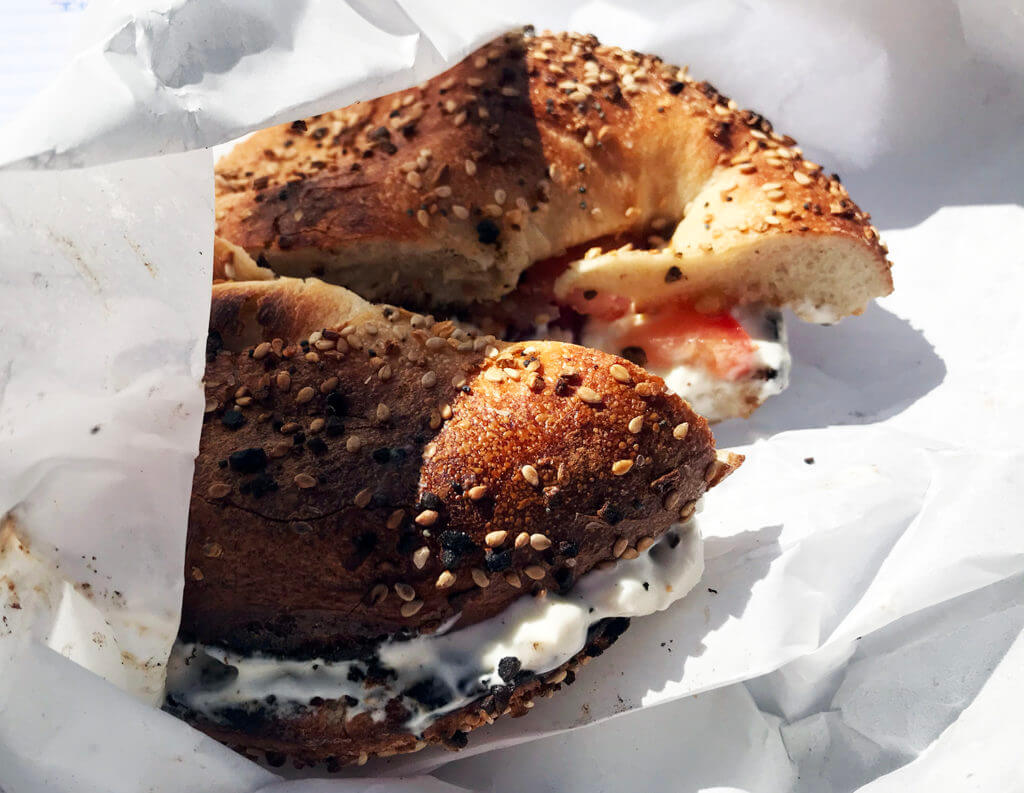 a toasted bagel wrapped in white paper