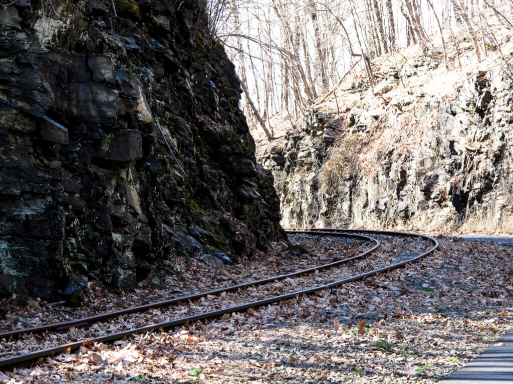 a railroad track winds between a rock cut on the Maybrook Trailway