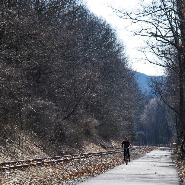 A lone cyclist on the Empire State Trail Maybrook segment, with a hilly background